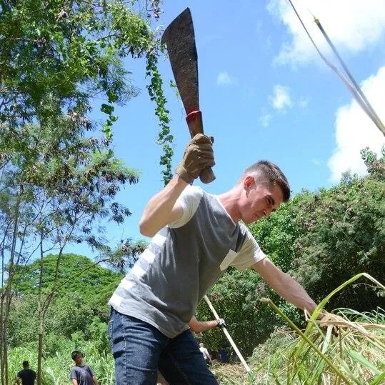 A person clearing vegetation with a machete